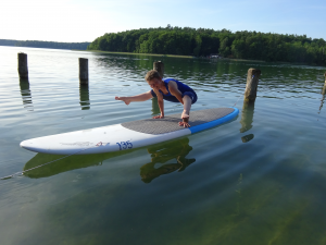 Angela hält eine Yoga-Asana auf dem SUP