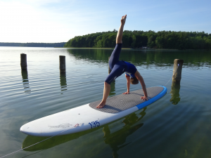 Angela hält eine Yoga-Asana auf dem SUP