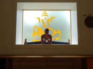 Angela im Spagat vor Ganesha im Fenster, Yogaraum